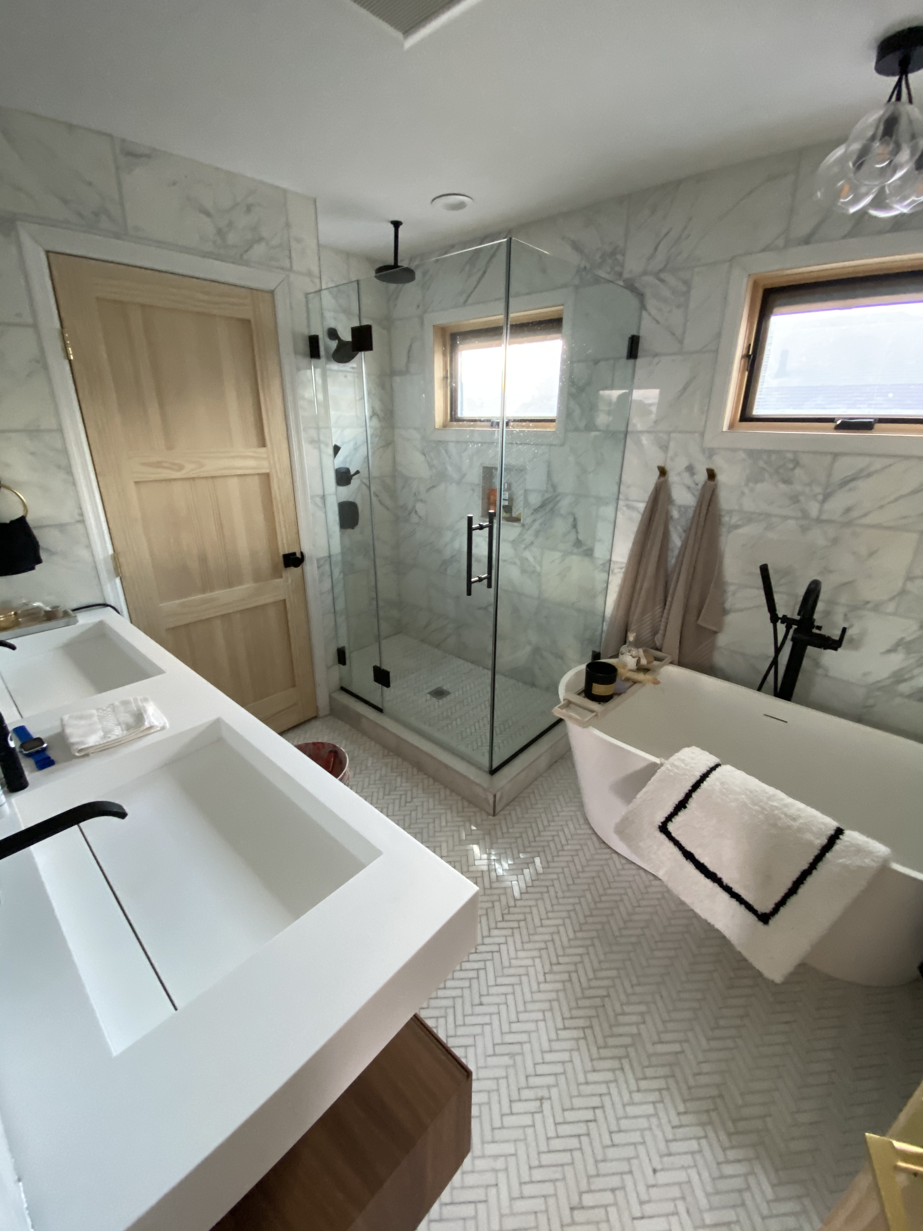 Luxury bathroom renovation with marble tile walls, glass shower enclosure, and freestanding bathtub