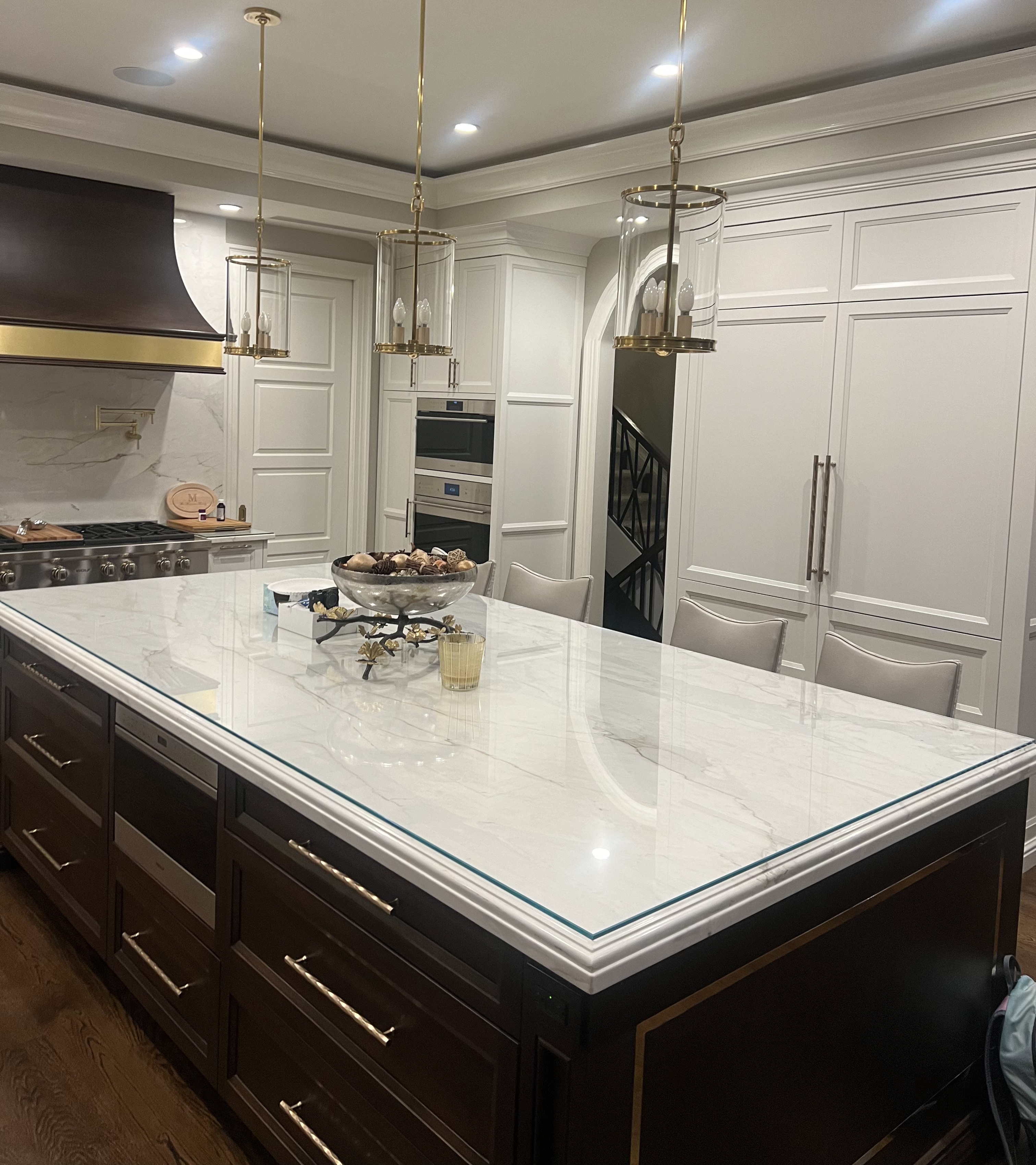 Luxury kitchen renovation with marble island, white cabinetry, and brass pendant lighting